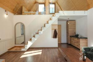 a white staircase in a living room with wooden ceilings at Chalets by Hotel Transalpin in Obarsia-Lotrului