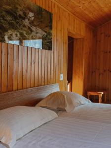 a bedroom with two beds and a wooden wall at Le Refuge Hotel Restaurant in Ayer