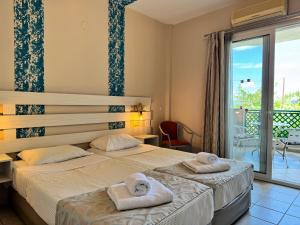 two beds in a hotel room with towels on them at Aegean Sun Hotel in Skala Rachoniou