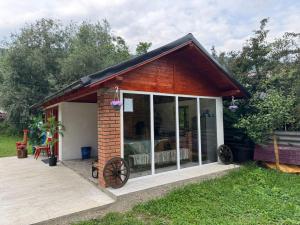 a small house with a large window and a deck at Casuta -Dor de Munte -Ceahlau in Bistricioara