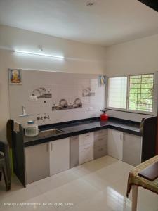 a kitchen with white cabinets and a black counter top at Wale's Hilltop Villa in Kolhapur
