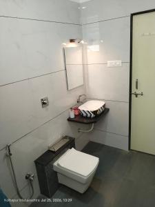 a white bathroom with a toilet and a mirror at Wale's Hilltop Villa in Kolhapur +3 photos