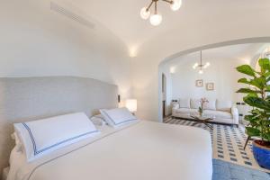 a bedroom with a white bed and a living room at San Montano Resort & Spa in Lacco Ameno