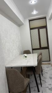a white table and chairs in a room with a window at АК Кеме in Osh