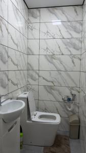 a bathroom with a white toilet and a sink at АК Кеме in Osh