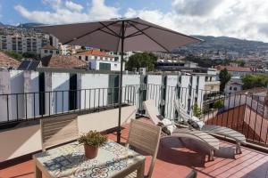 a patio with a table and an umbrella on a balcony at BJ Apartments Funchal in Funchal