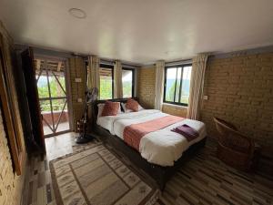 a bedroom with a bed in a room with windows at Rock Garden Resort in Pokhara