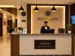 a man sitting at a reception counter in a lobby at Hotel Nirmla Residency in Brahmapur