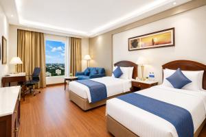 a hotel room with two beds and a window at Hotel Nirmla Residency in Brahmapur