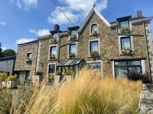 a brick building with windows and plants in front of it at Hotel Le Beau Séjour in Nassogne