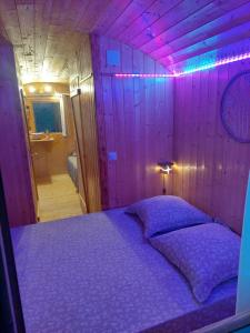 a bed in a room with a purple wall at La roulotte enchantée in Le Boissenet +6 photos