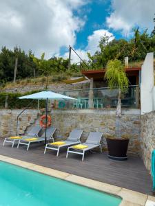 a patio with chairs and an umbrella next to a pool at Casinha do Orjal in Ponte de Lima