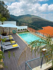 a swimming pool with chairs and an umbrella at Casinha do Orjal in Ponte de Lima
