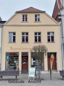 a building with a bench in front of a store at Tangermünde Zum S c h m u c k Giebel - Pension & FeWo in Tangermünde