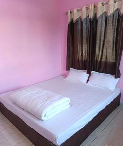 a pink bedroom with a large bed with white sheets at Shiva Homestay Dwarka in Dwarka