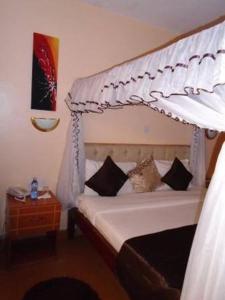 a bedroom with a white canopy bed with pillows at Tumaini Guest Home in Gathundia