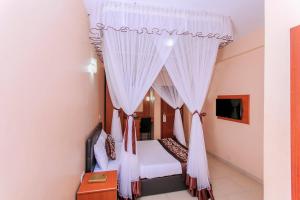 a bedroom with a bed with white curtains at Tumaini Guest Home in Gathundia