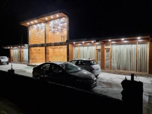 two cars parked in front of a building at night at Gaunney Valley - Tirthan Valley in Manāli