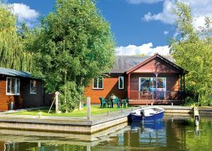 a house on a river with a boat in the water at Bure-Way And Rosemere in Wroxham +6 photos
