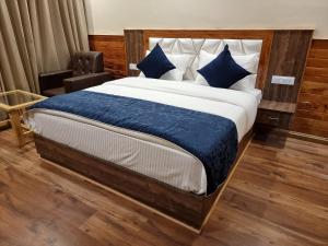 a bedroom with a large bed with blue pillows at Gaunney Valley - Tirthan Valley in Manāli