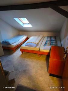 two beds in a attic room with a window at Centrum Panzió VIP in Kaposvár