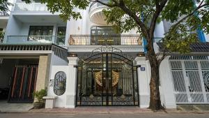 a white house with a black gate and a tree at Mai Song Linh in Phan Rang–Tháp Chàm