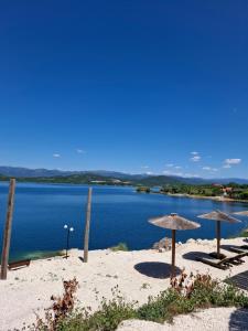 a beach with two umbrellas and a body of water at Lake Apartment Krupac in Nikšić