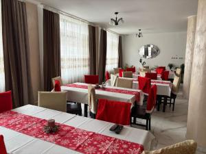 a restaurant with tables and chairs with red table cloth at Pensiunea Grande Lepsa in Lepşa