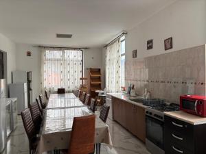 a kitchen with a long table with chairs and a stove at Pensiunea Grande Lepsa in Lepşa