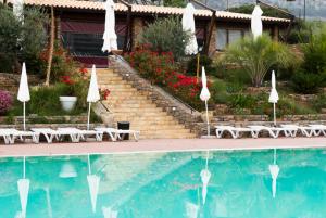 a swimming pool with chairs and umbrellas and a house at Valle Himara in Piana degli Albanesi