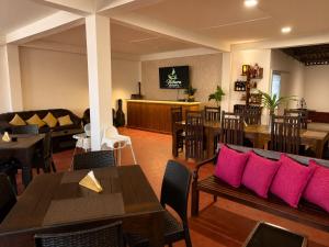 a restaurant with tables and chairs with pink pillows at Wihara Cottage Sigiriya in Sigiriya