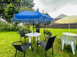 a group of tables and chairs with a blue umbrella at Levandų šeimyniniai apartamentai su vonia ir sodu in Ryškėnai