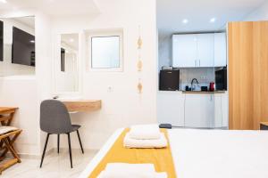 a kitchen with white cabinets and a table and a chair at Syntagma Luxury Suites 1 in Athens