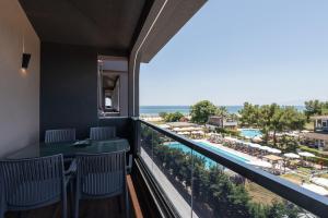 a balcony with a view of the pool and the ocean at OLYMPIADA GIRNI Suites in Paralia Katerinis