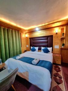 a bedroom with a large bed with blue pillows at K2 Alpine Hotel in Pahalgām