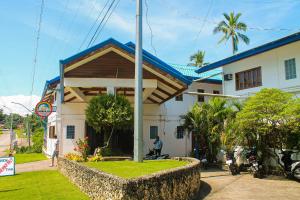 a white house with a blue roof and a palm tree at Rainbow Bay Beach & Dive Resort in Siquijor