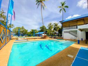 a large blue swimming pool with palm trees in the background at Rainbow Bay Beach & Dive Resort in Siquijor