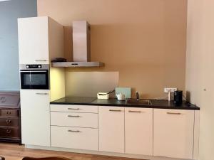a kitchen with white cabinets and a sink at historic city apartment with private parking in Gouda