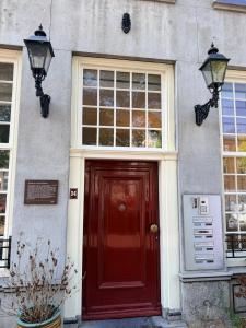 a red door of a house with two windows at historic city apartment with private parking in Gouda
