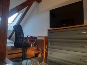 a bedroom with a dresser with a tv and a chair at Loft przy Starym Mieście in Jarosław +11 photos