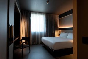 a hotel room with a bed and a chair and a window at Conterraneo Hotel in Marcianise