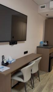 a desk with two chairs and a television on a wall at Na More Центр Семейного Отдыха in Kapchagay