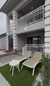 two benches sitting on the grass in front of a house at Na More Центр Семейного Отдыха in Kapchagay