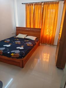 a bedroom with a bed and a window with orange curtains at Sheelas stay in Guruvāyūr