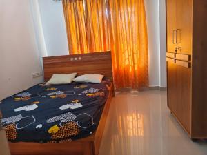 a bedroom with a bed and a window with an orange curtain at Sheelas stay in Guruvāyūr