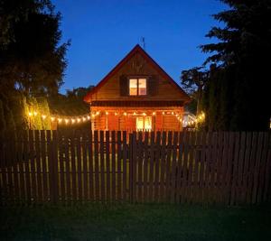 a house with christmas lights in front of a fence at Leonówka in Nowogród
