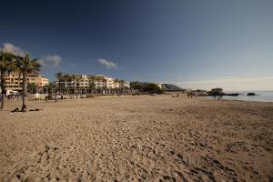 a beach with people sitting on the sand and buildings at La Sort Boutique Hotel in Moraira