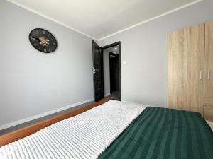 a bedroom with a bed and a clock on the wall at Apartament przy Kauli in Inowrocław