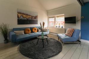 ein Wohnzimmer mit einem blauen Sofa und einem Tisch in der Unterkunft De Fluessen Loft in Elahuizen