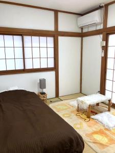 a bedroom with a large bed and windows at The Village House 1 in Hadano